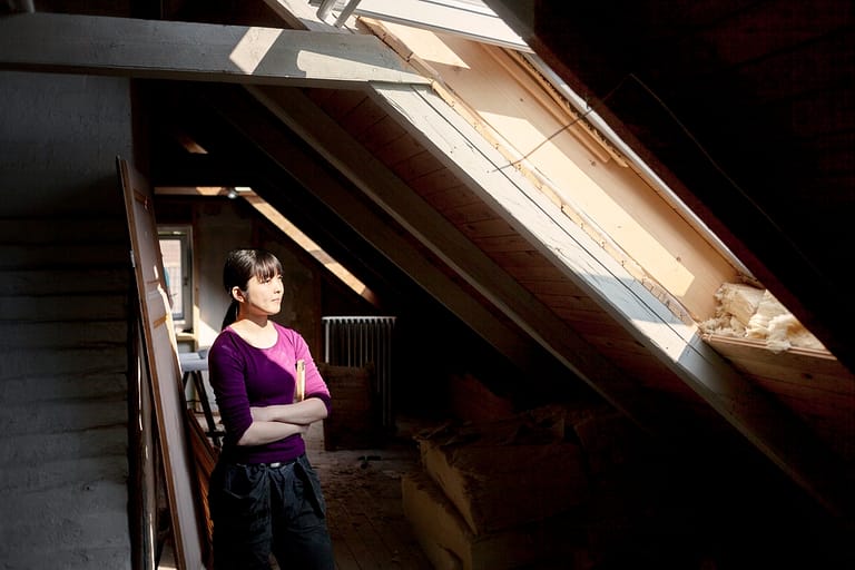 Woman in old loft looking at sunlight